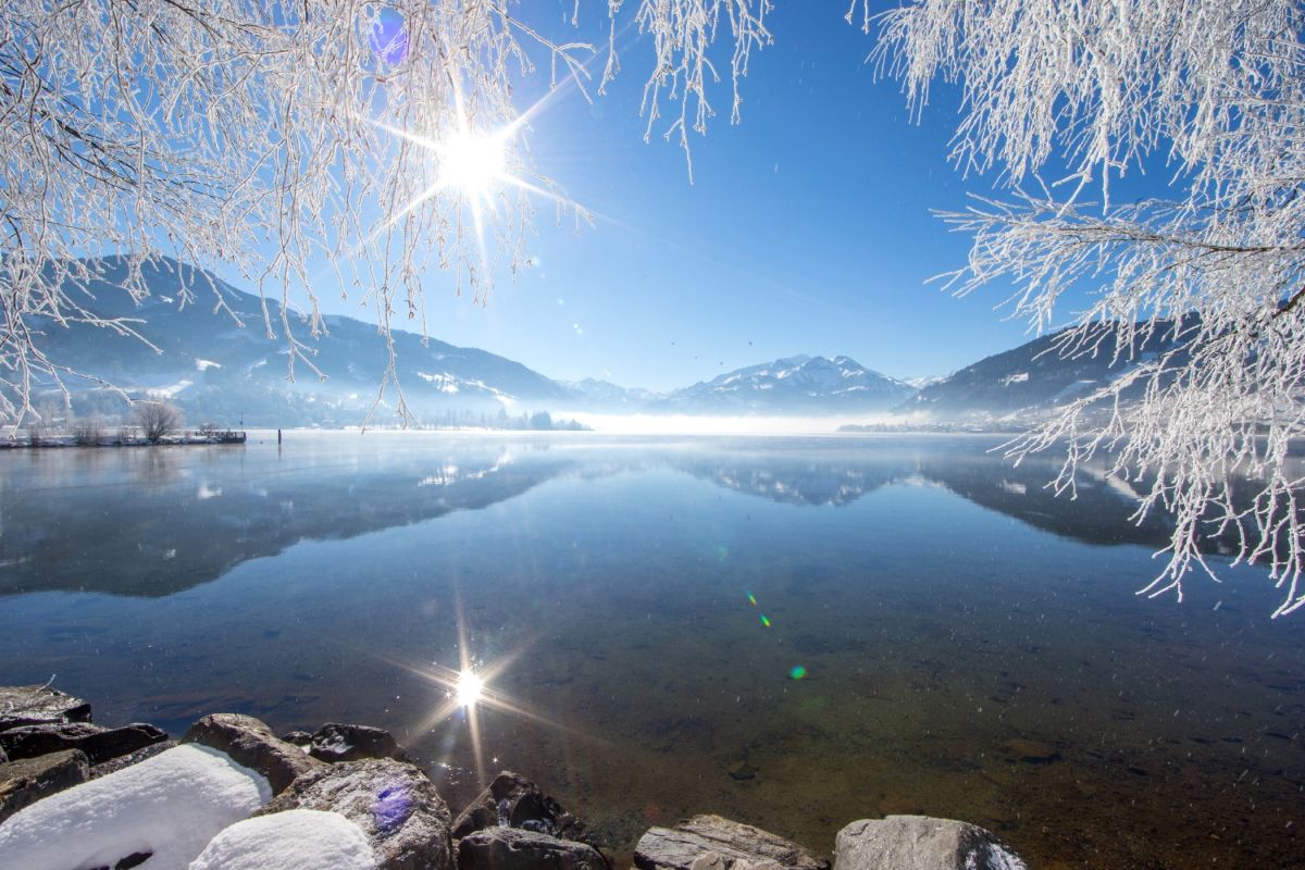 Winterlicher Zeller See mit verschneiten Bäumen und Bergpanorama
