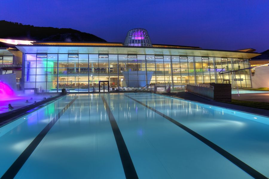 Beleuchteter Außenpool der TAUERN SPA am Abend