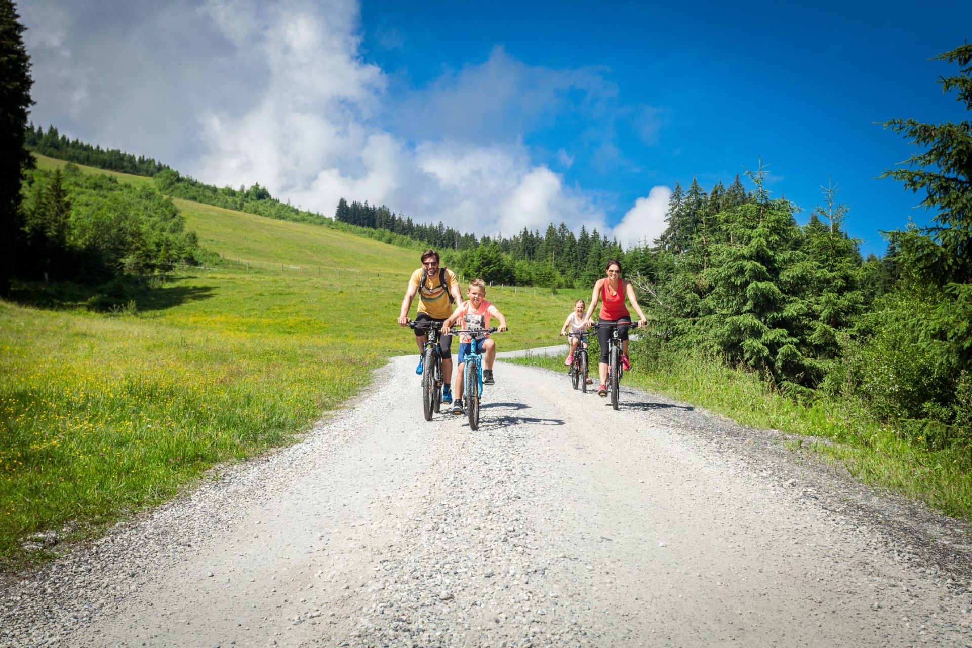 Familie beim Radfahren auf einem Forstweg in Zell am See