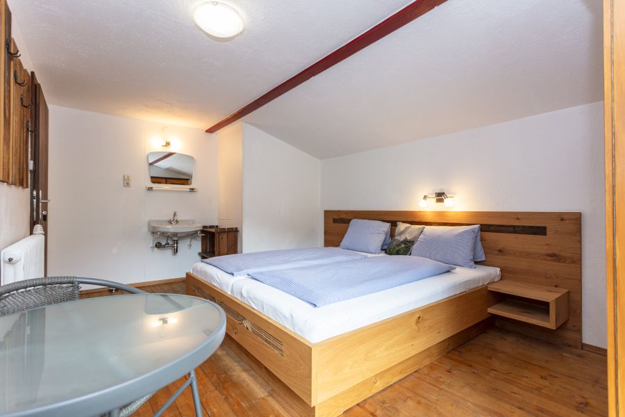 Schlafzimmer mit Doppelbett und kleinem Glastisch
