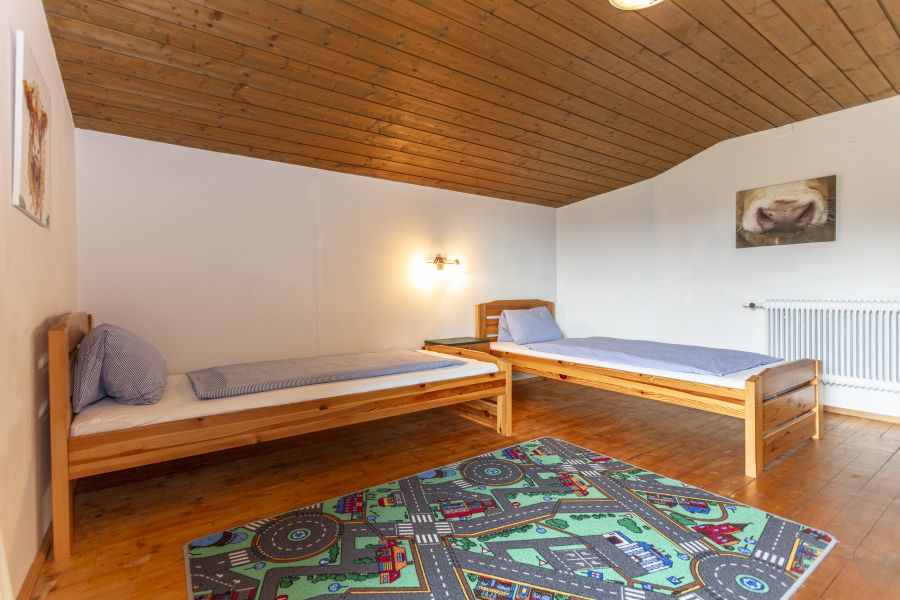 Schlafzimmer mit zwei Betten und Spielteppich